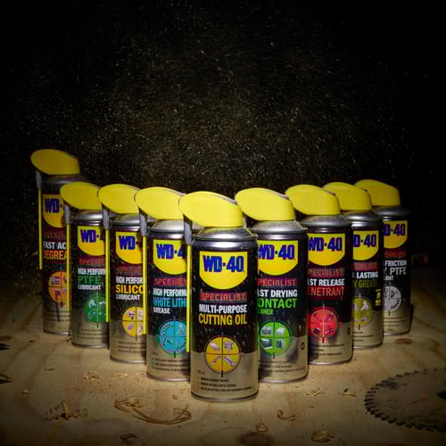 WD40 Specialist set lined up in an arrow formation on a piece of wood with sawdust in the air
