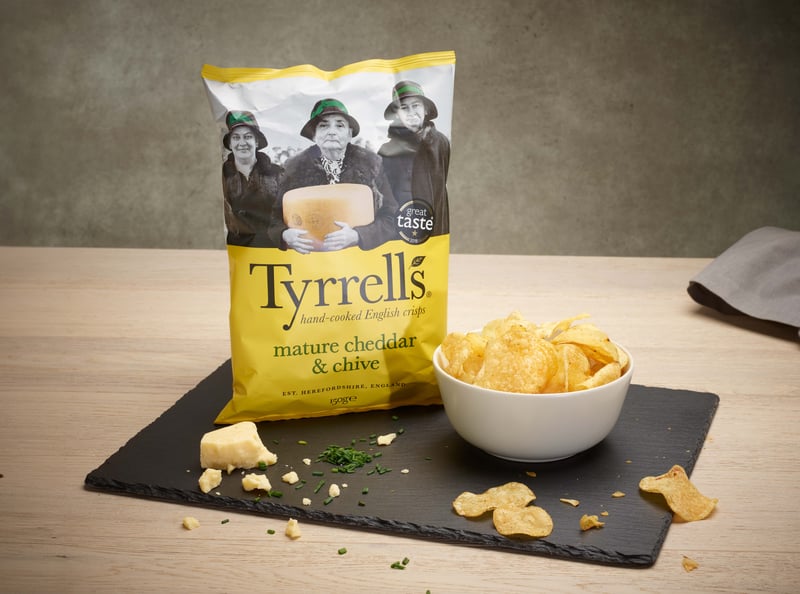 Tyrrell's crips packaging photography on a piece of slate, next to a bowl of the crisps, on a table