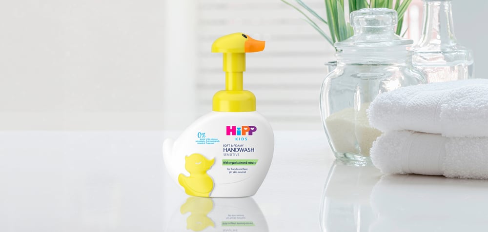 HiPP Kids soap bottle with yellow duck pump nozzle on a table with white towels and a jar.