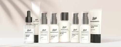 Selection of Boots products in white bottles on a satin pink background.
